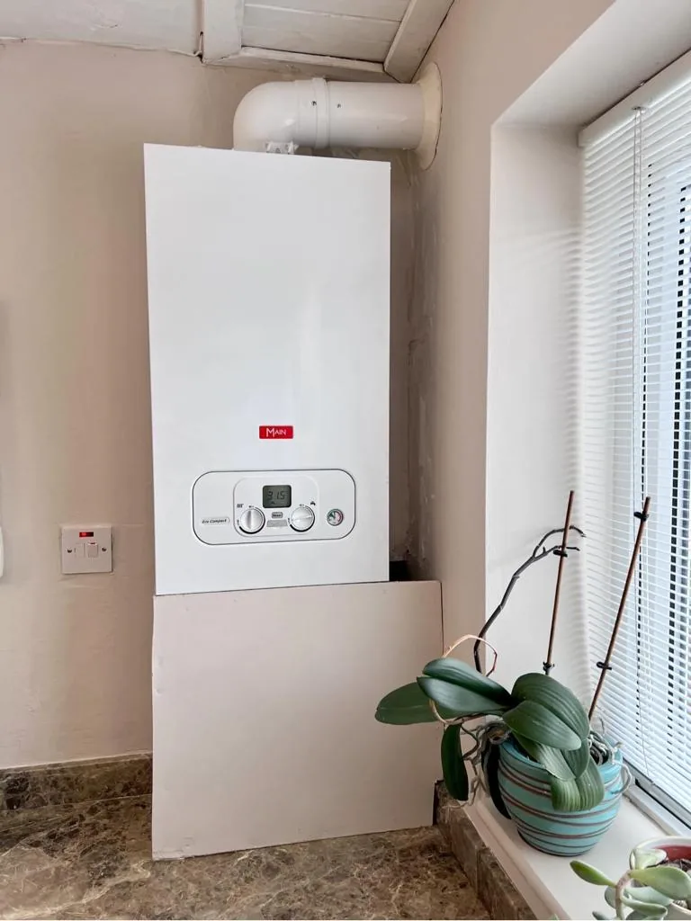 A boiler neatly installed beside a window in a finished room
